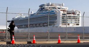 Cruise ship on the water behind a fence and traffic cones