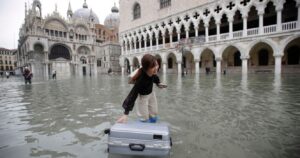 Tourist in Venice with her luggage floating in floodwater